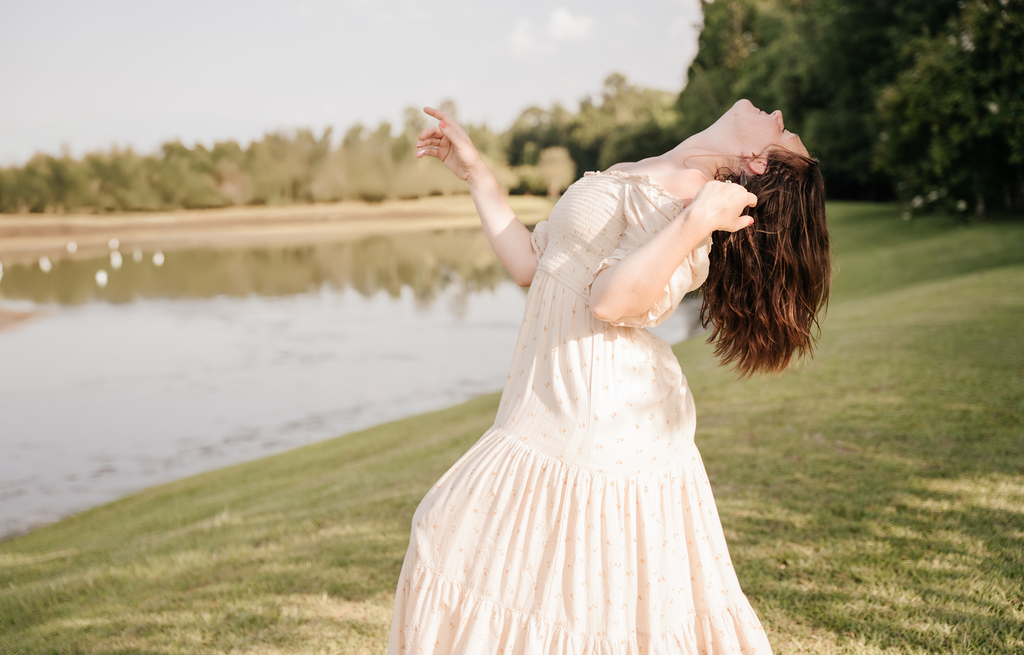 A dancer in a worship pose beside the water