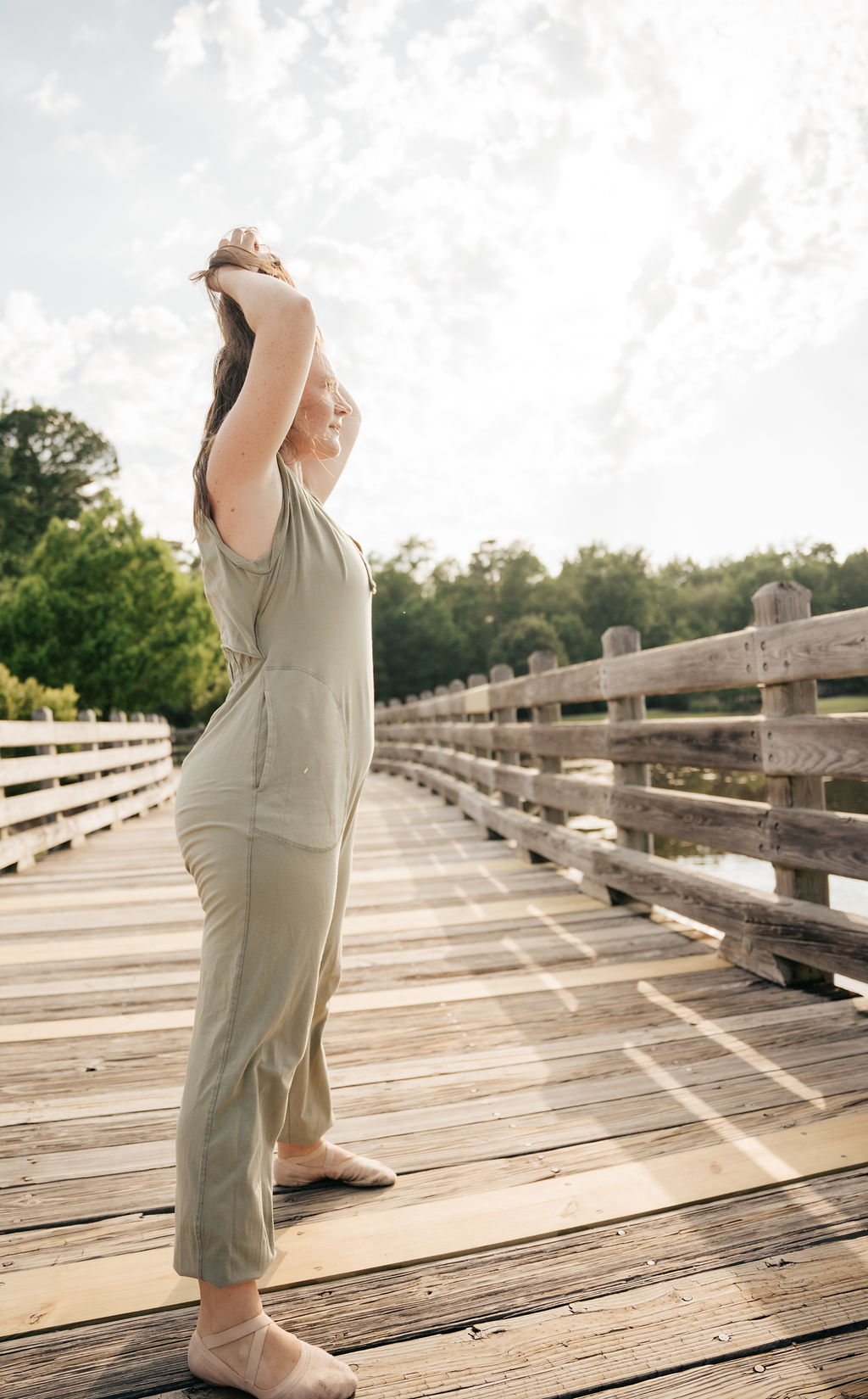 A dancer reaching overhead on the boardwalk at sunset
