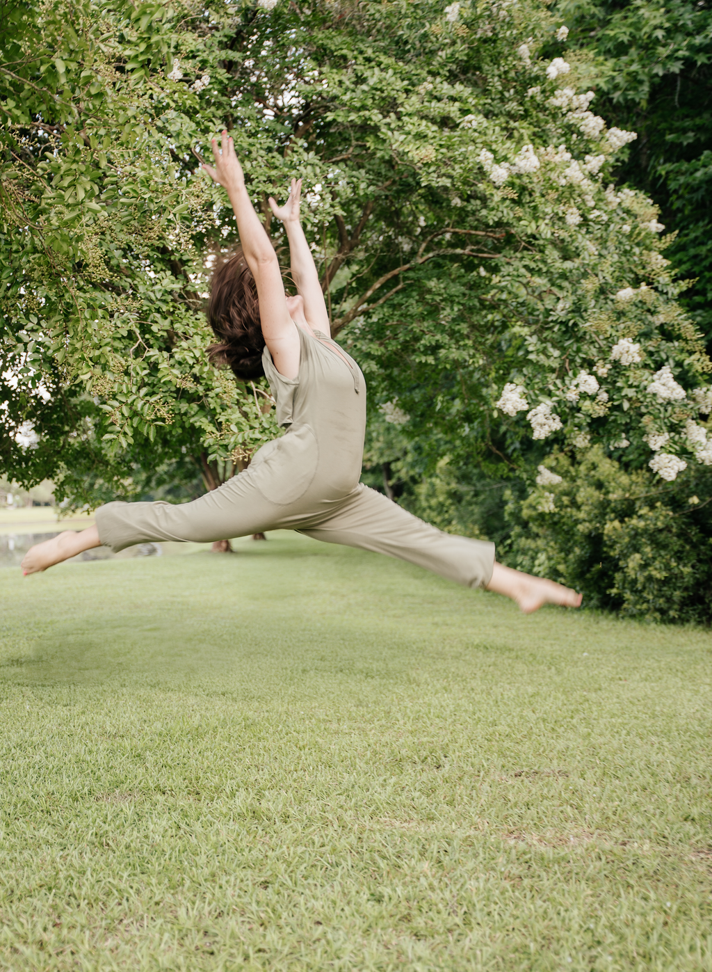 A dancer mid-leap on a sunlit lawn