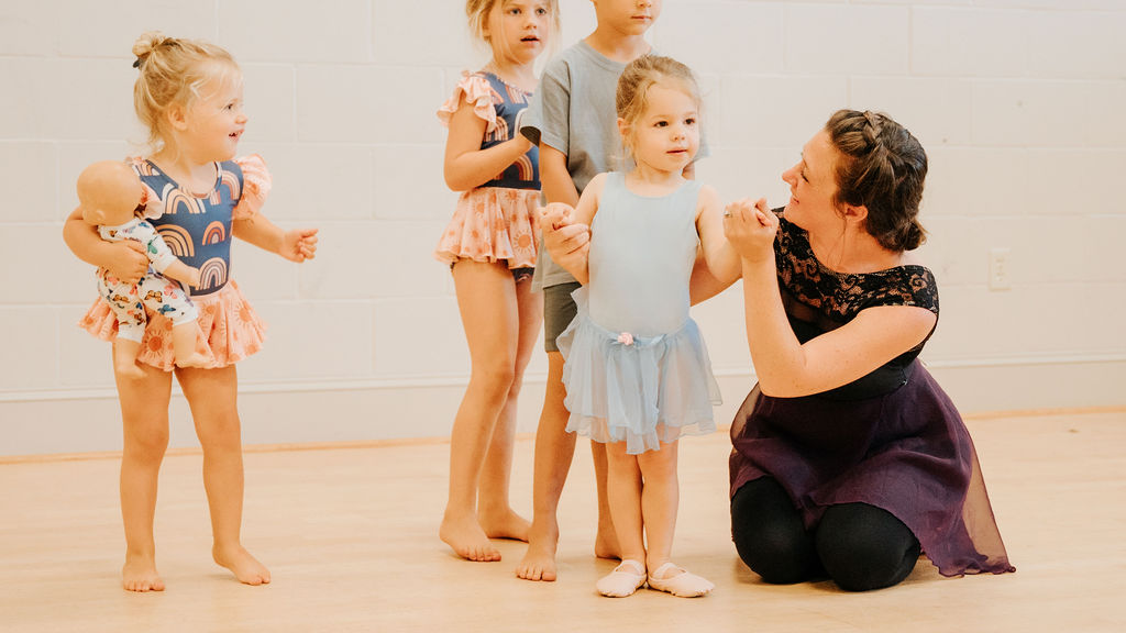 A row of little dancers holding hands with their teacher