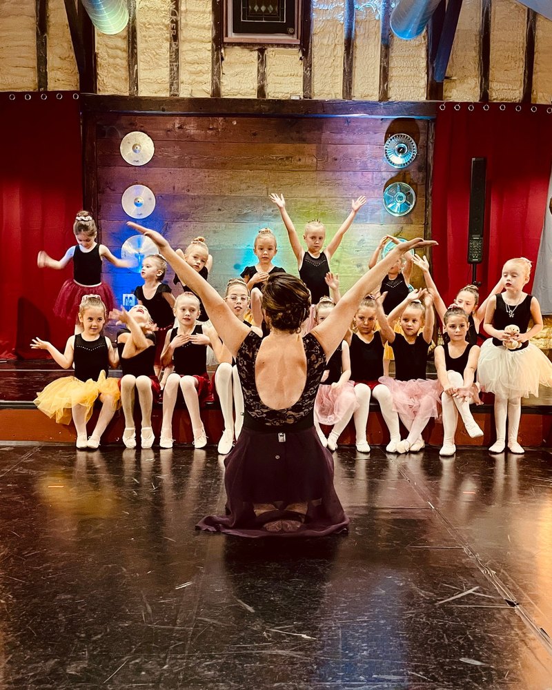 The whole class on stage with their instructor, arms lifted together