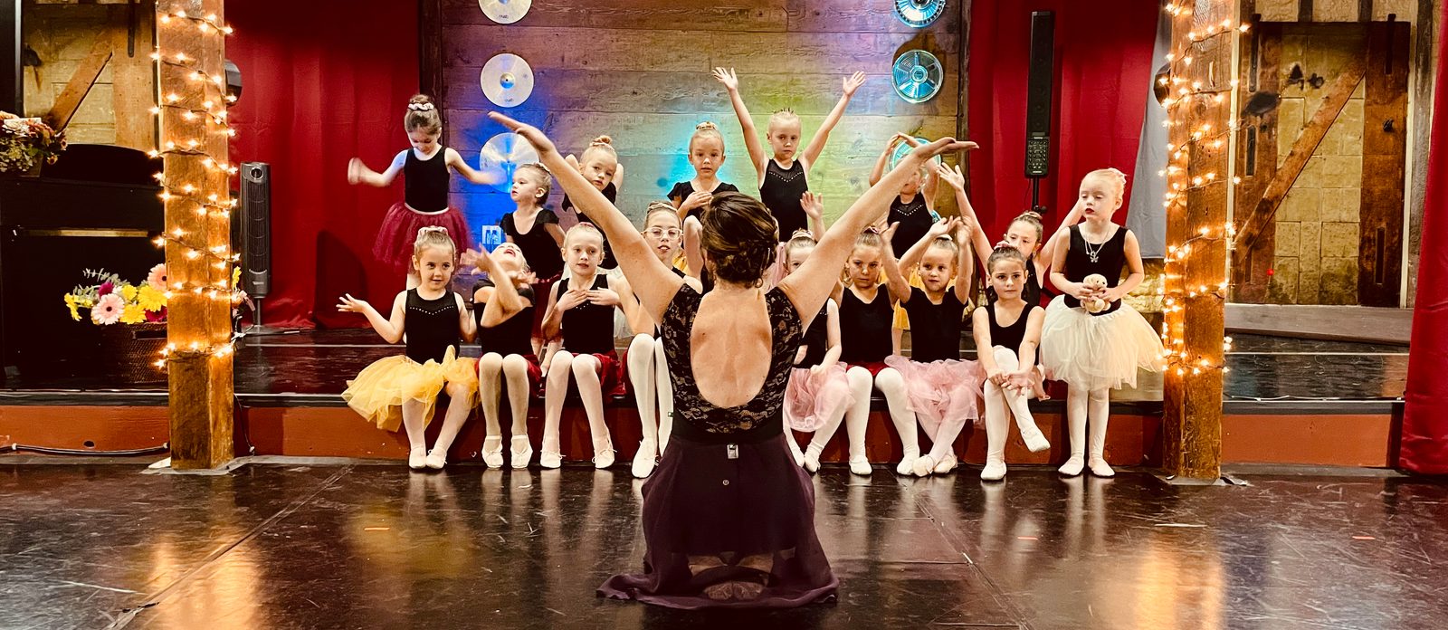 The whole class on stage with their instructor, arms lifted together