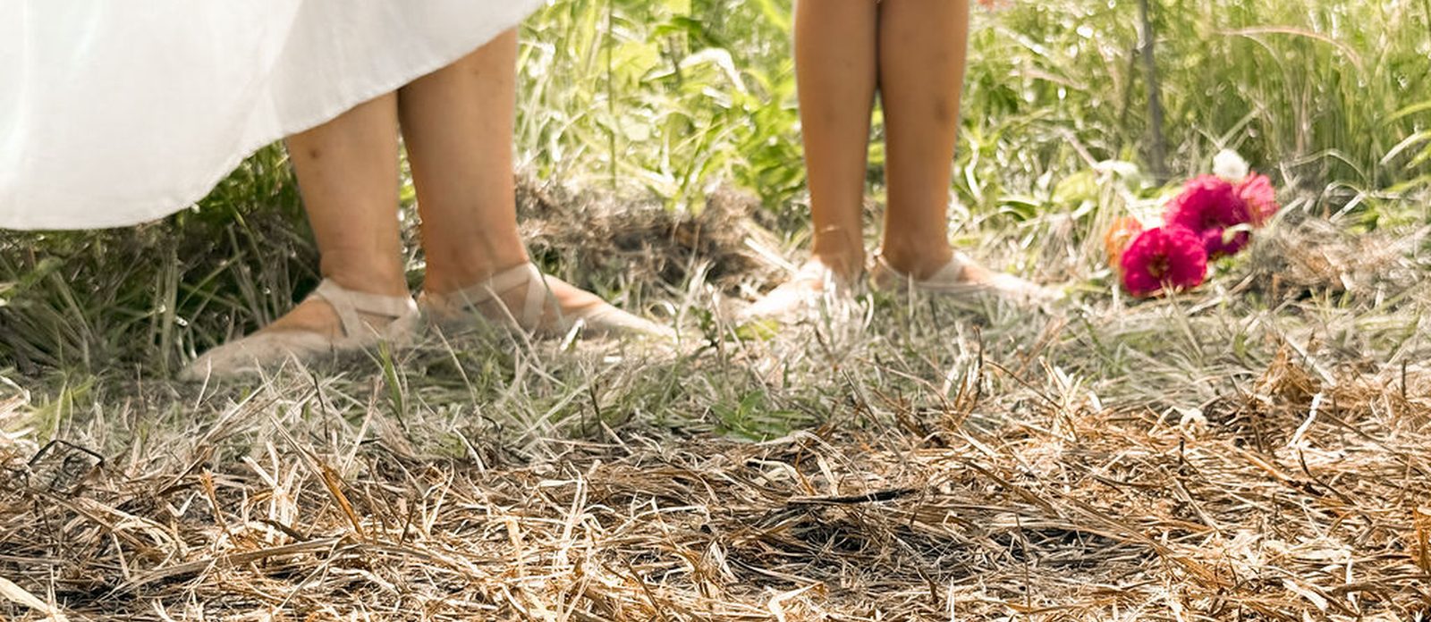 Pointe shoes and bare feet resting side by side in the grass